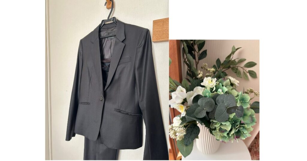 ハンガーにかかったパンツスーツと、花瓶に生けられた緑の白の花束