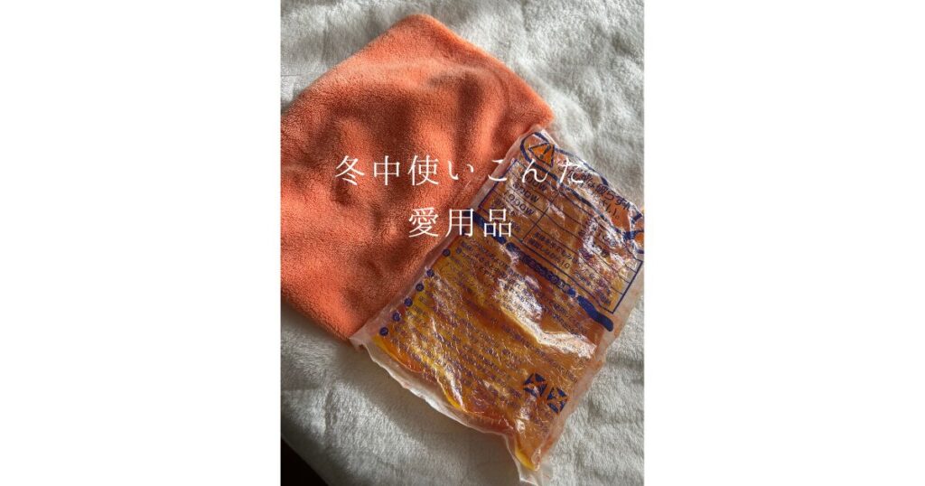 レンジで温めるタイプの湯たんぽとオレンジ色の湯たんぽカバーと、冬中使い込んだ愛用日の文字の画像
